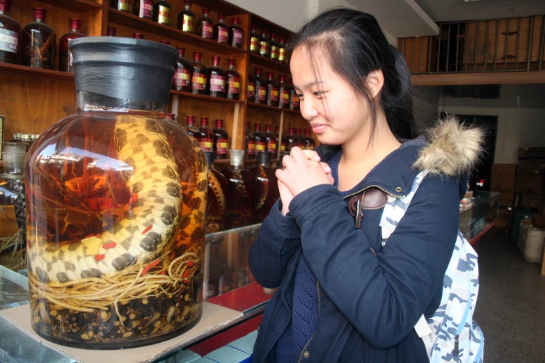 a woman looks at a jar with a picture in it