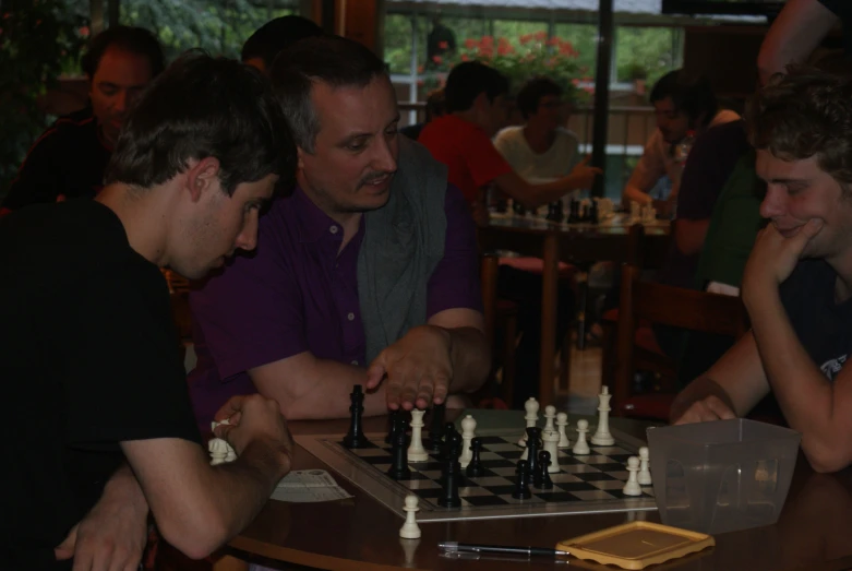 a group of men sitting at a table playing chess