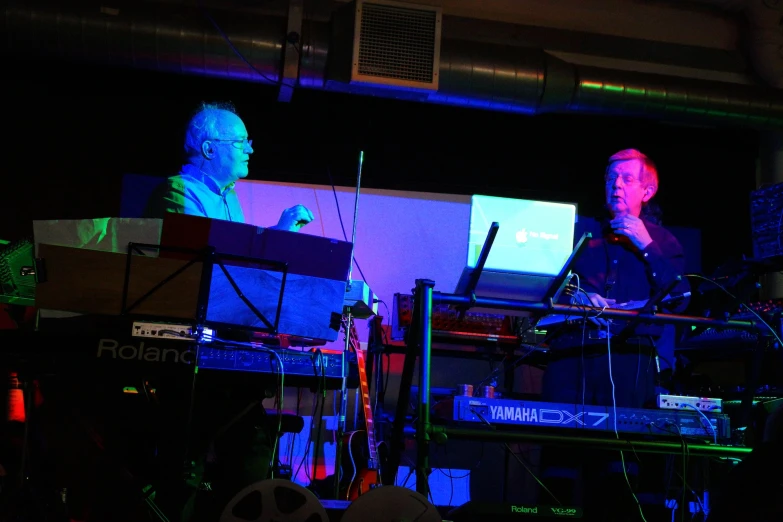 two men playing instruments while standing next to each other on stage