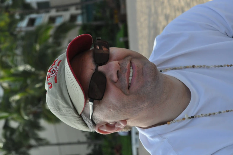 a smiling man is wearing a necklace and glasses