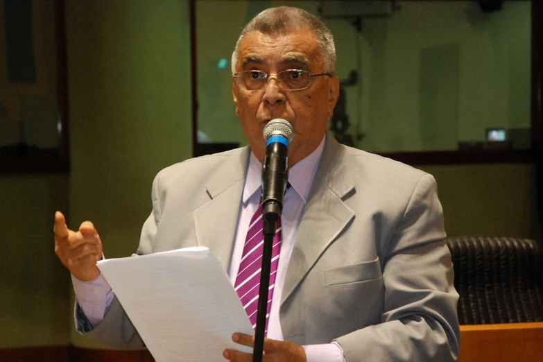 a man in suit and tie speaking at microphone