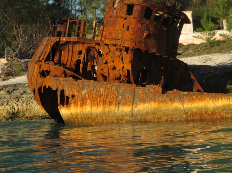 an old rusted boat is standing in the water