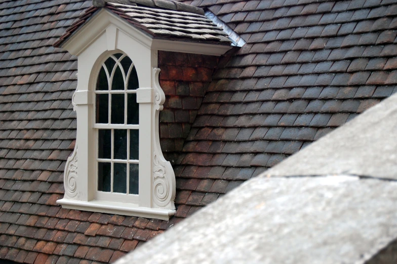 a white window on a brown building with brown shingles