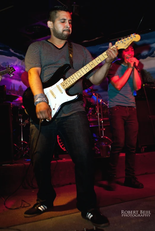 two men standing on stage holding onto guitars