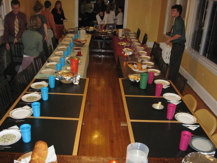 a long wooden table with plates and cups on it