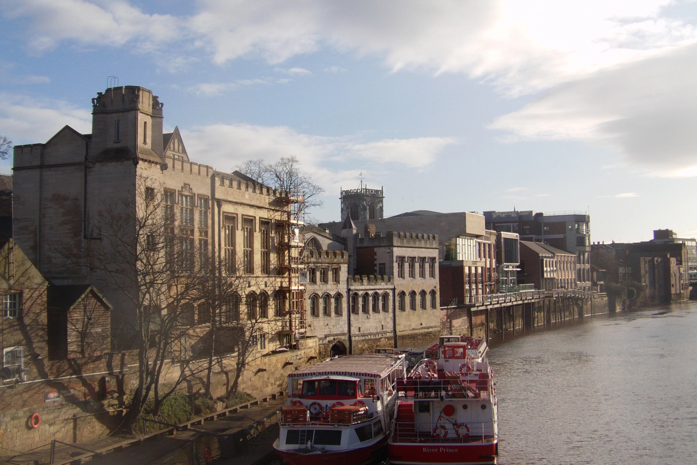 two barges are parked in front of buildings on a river