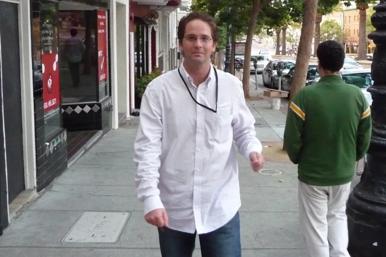 a man walks down the sidewalk with a skateboard