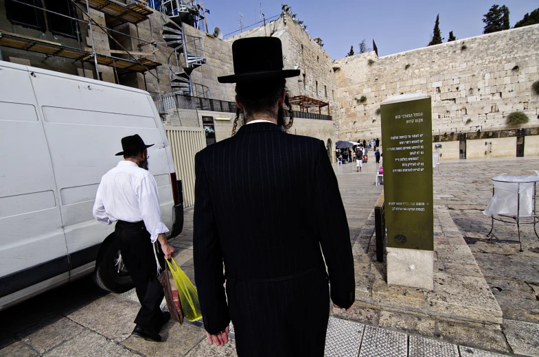 a man wearing a hat walking beside an old building