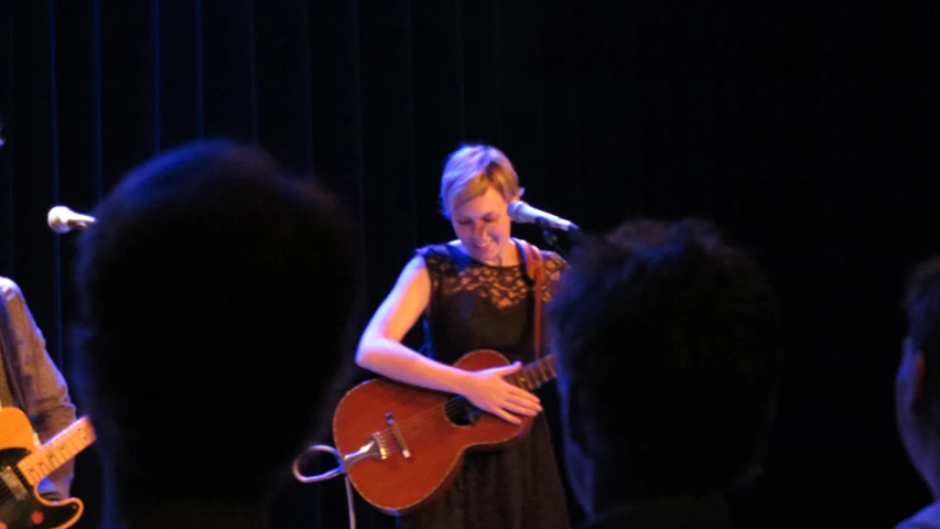 a woman playing a guitar in front of a microphone
