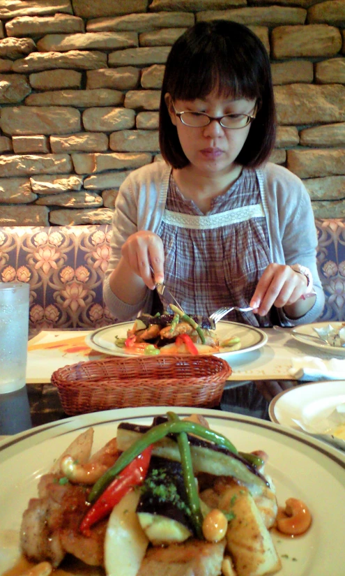 a lady with glasses eating food at a restaurant