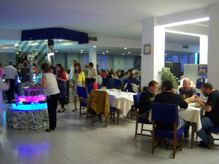 some people are gathered at tables with white and purple cloths