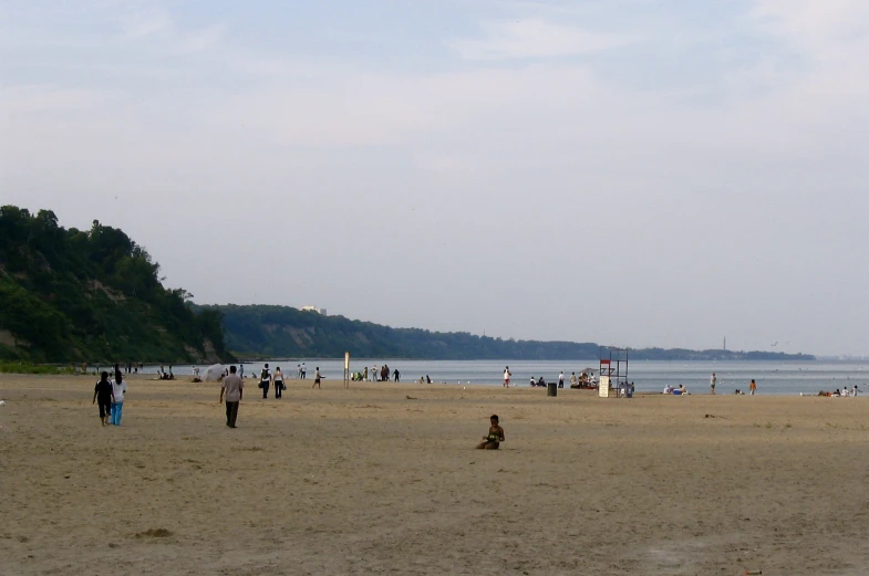 a group of people walking on the beach with the sky in the background