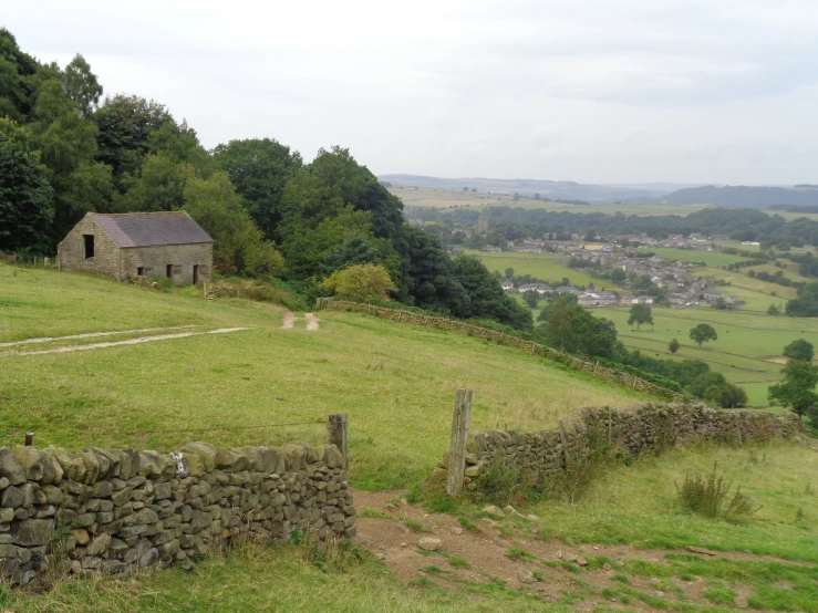 a stone fence and wooden posts on a grassy hill side