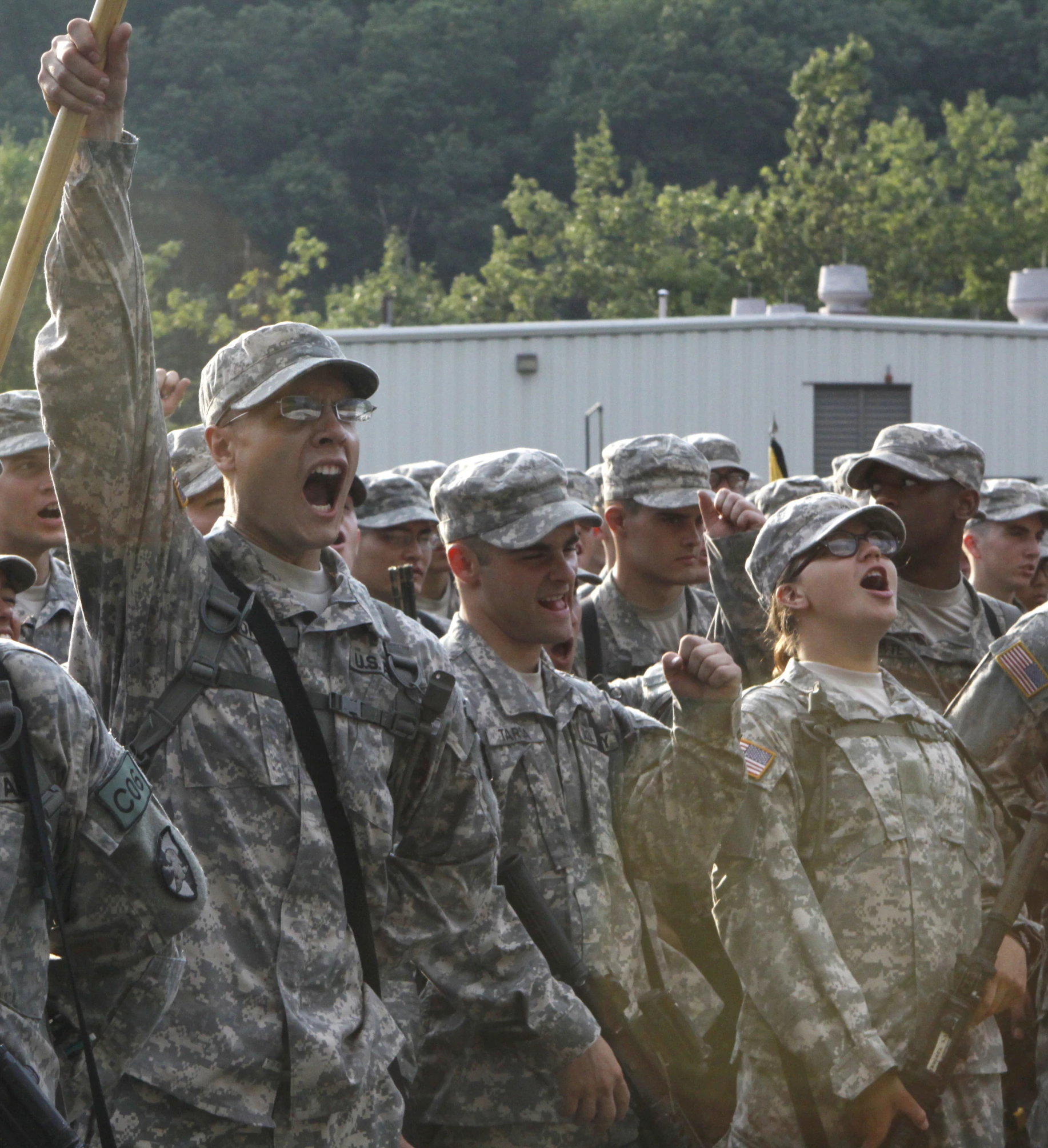 many soldiers are marching and one is holding an umbrella