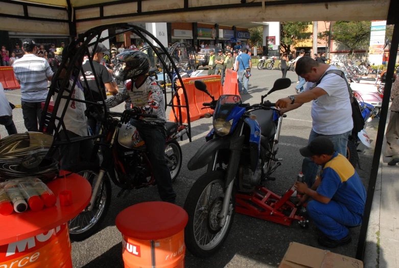 some guys are repairing a motorcycle near many others