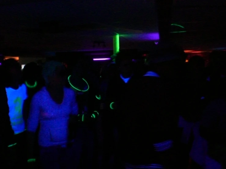 a crowd of people are standing in the dark with neon rings around their necks