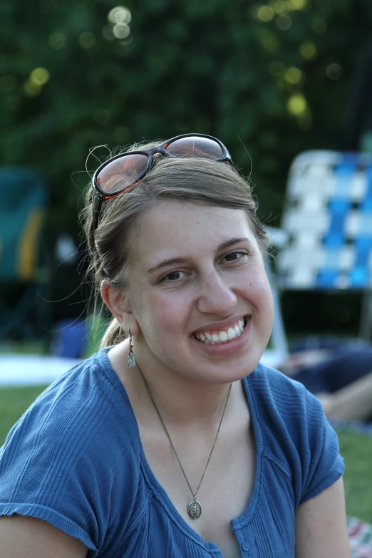 a pretty woman with sunglasses and a blue shirt smiles