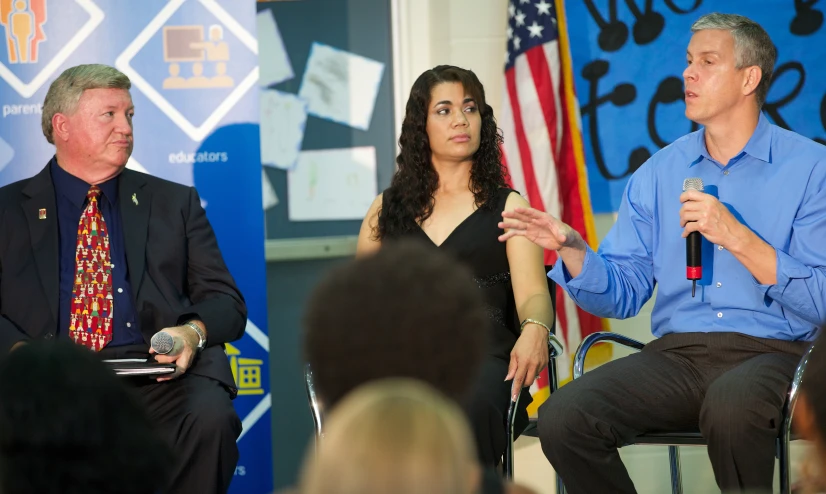 two people sitting down with microphones, talking to someone on the side