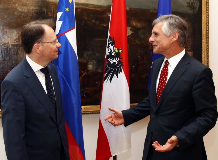 two men standing next to each other near flags