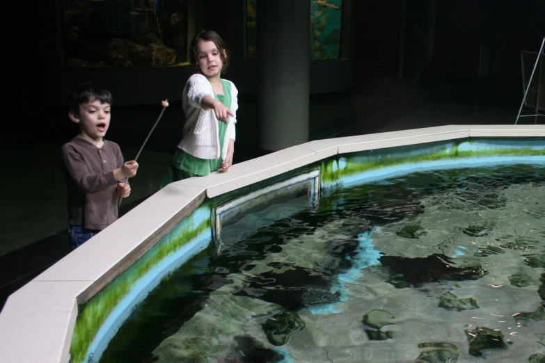 two children are playing with water in a museum