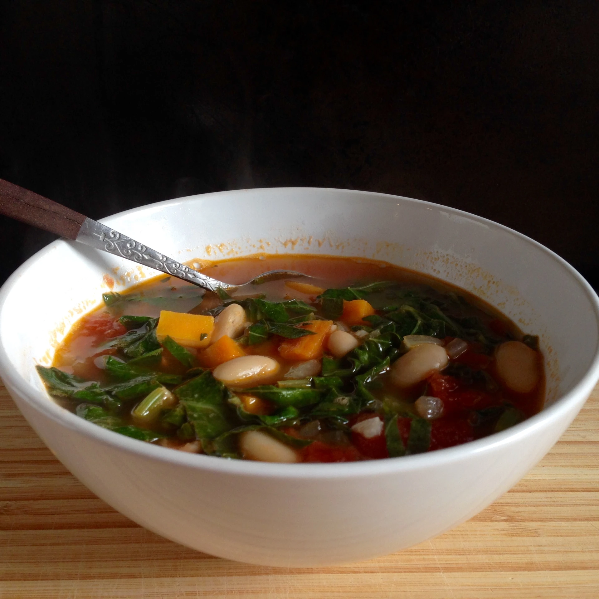 a bowl of soup with beans and greens