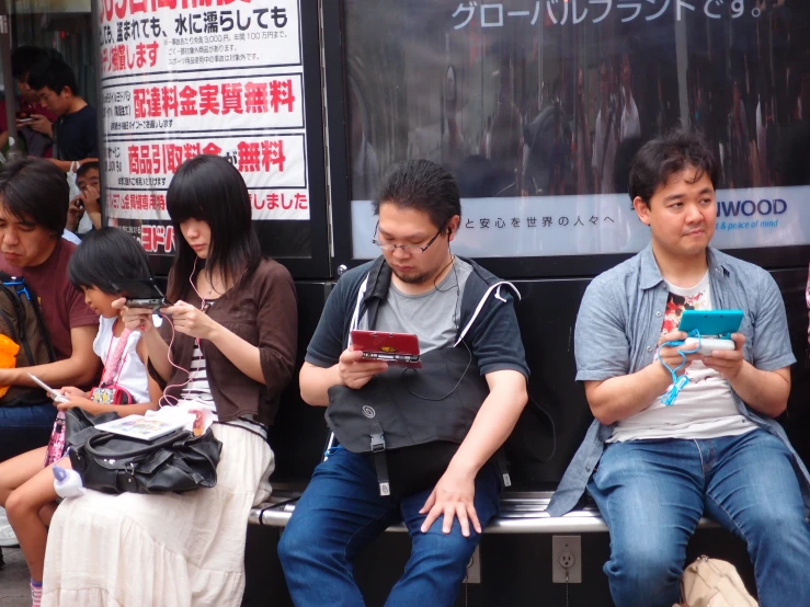 three people sitting on a bench using their cellphones