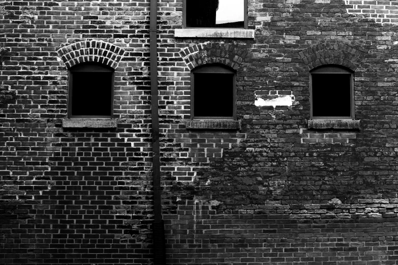 a black and white picture of a brick wall with several windows