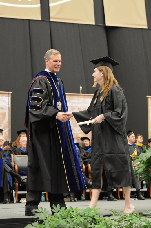 a graduate shakes hands with another woman