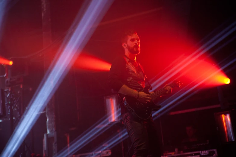 a man standing on stage with red and purple lights behind him