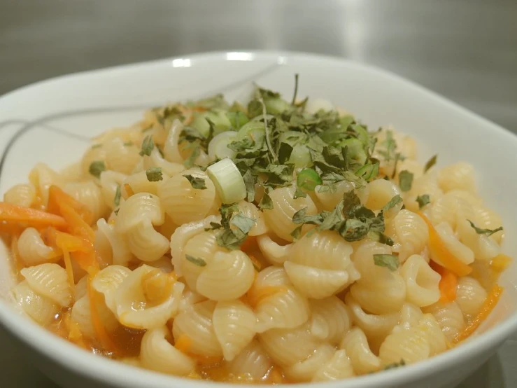 pasta dish on white bowl with silver spoon and wooden table