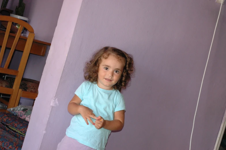 a child standing in the corner of a room with her hands near her waist