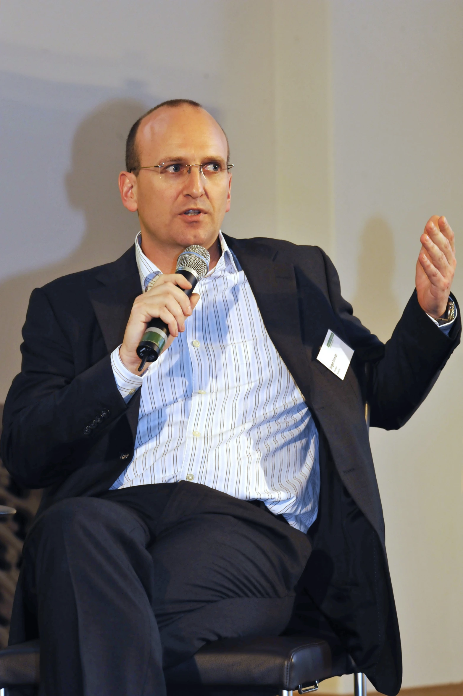 a man sits in a chair and holds a microphone