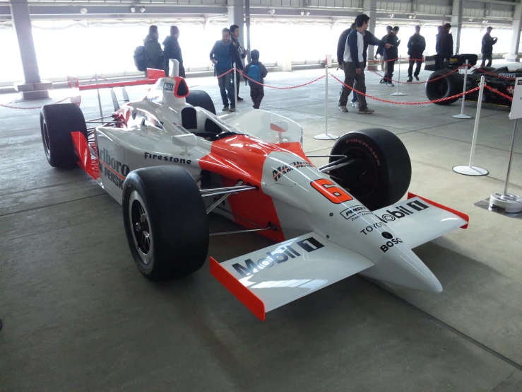 an upside down race car in a building with people standing around