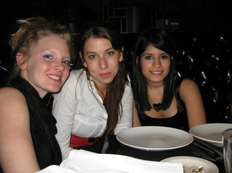 three women are posing for a picture at a restaurant