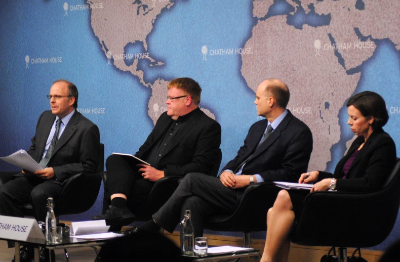 three people sitting in chairs on a panel