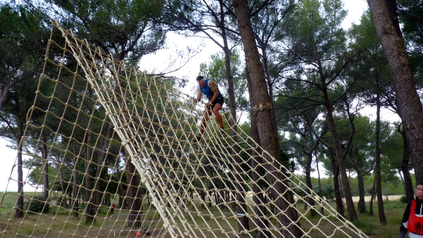 a man on a rope bridge next to a forest