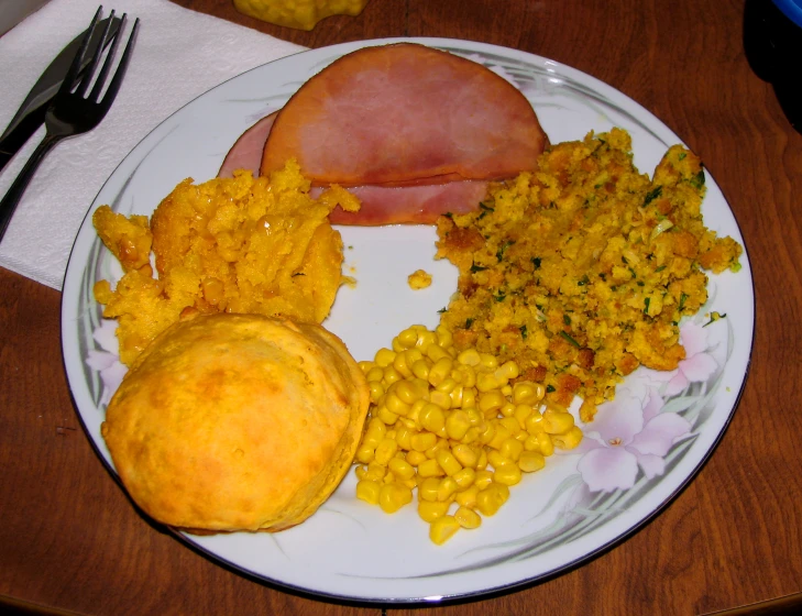 a white plate topped with corn, ham and sweet potato