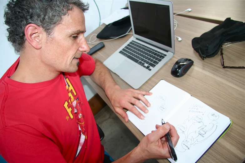 a man sitting at a desk with a notebook and pen