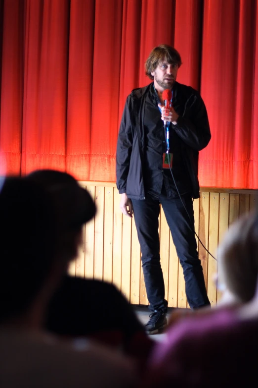 a man standing in front of a red curtain