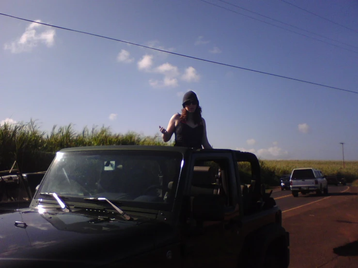 a woman in black shirt standing on top of a black jeep