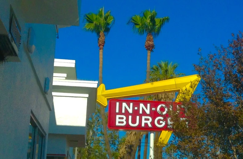 a sign with palm trees in the background