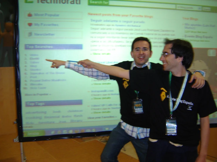 two guys in front of a screen with the thumbs up