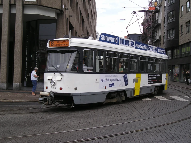 people stand in the middle of the street behind an old tram