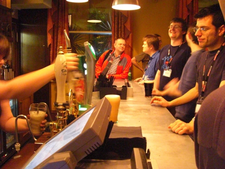 a group of people at a long bar pouring beer