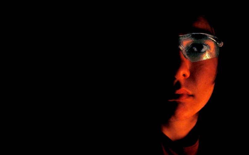 a man is illuminated in the dark with glasses