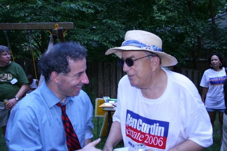 two men wearing hats and shirts sit at an event