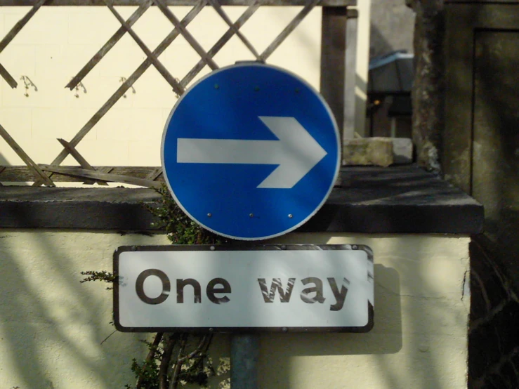 one way sign near a closed gate with an arrow on it