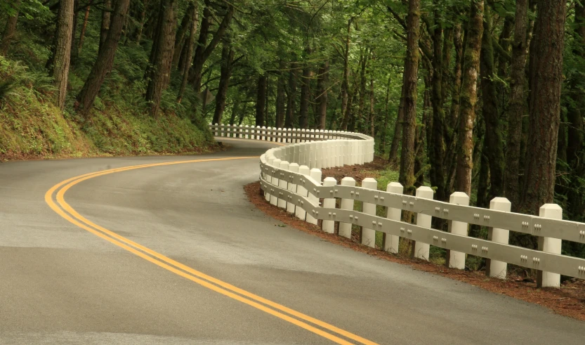 a curved roadway has many fences along both sides