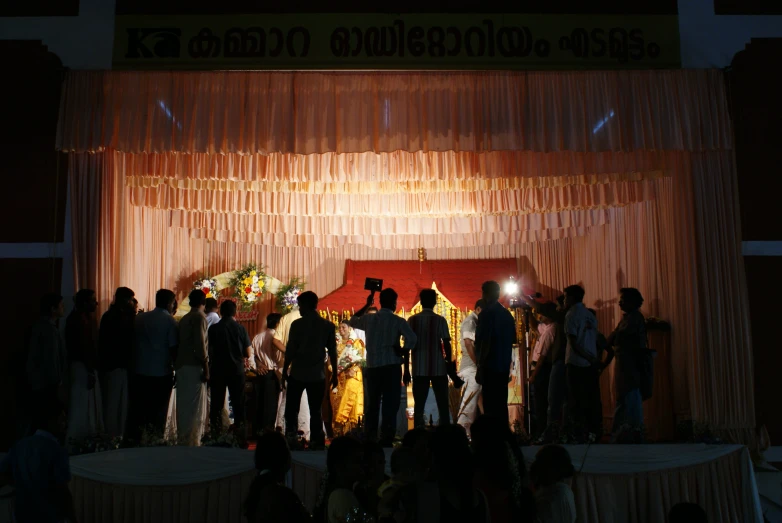 a group of people standing on top of a stage next to a curtain