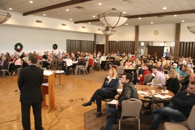 a large crowd is seated and listening to an audience